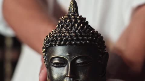 A Man Holding A Buddha Head Figurine