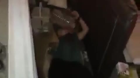 Guy green shirt tries to throw water container over his back but ends up falling backwards onto cardboard