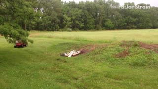 Fat guy tries to ride red lawnmower up dirt hill and falls back