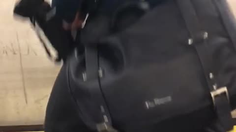 Man with umbrella in bag gets excited about train coming