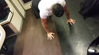 Guy does push ups on subway train