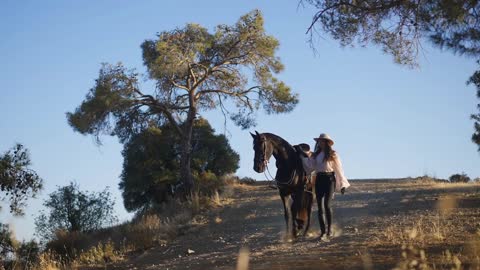 Confident young woman and graceful horse walking downhill