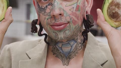 Young Tattooed Man Posing with Avocado Halves