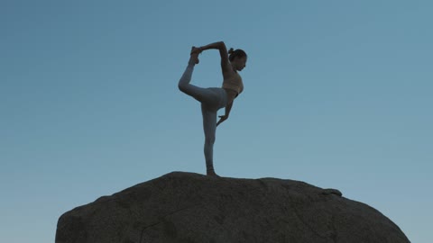 Woman doing yoga on a boulder