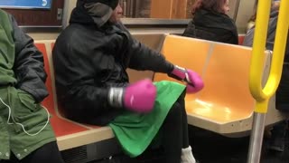 Man green skirt pink boxing gloves on train
