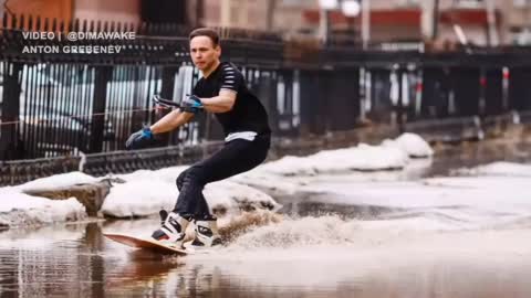 Watch the young men skiing on rainwater in the street
