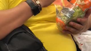 Guy yellow shirt eating salad out of bag