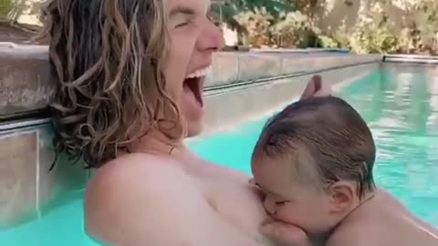 Funny baby trying to breastfeed from his father