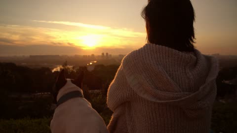 A woman with her dog watching the sunset
