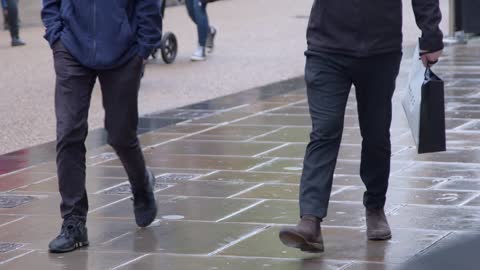 Medium Shot of Pedestrians Walking On Wet Pavement