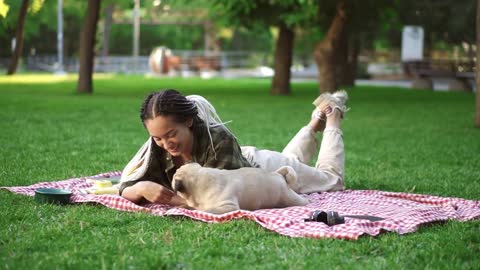 Woman with dreadlocks playing with her dog on grass