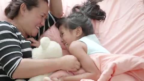 Funny Mom And Lovely Child Are Playing In Bedroom.