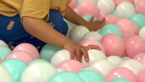 a child playing in a ballpit