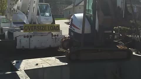 Crane lowering Track ho into basement.