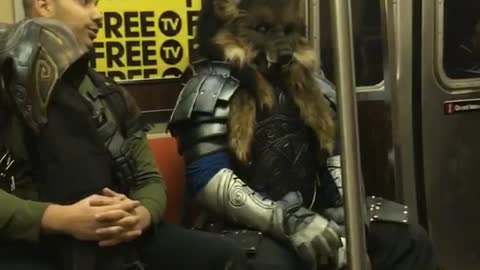 Woman sings "into you" on subway station, man in wolf costume sits behind her casually