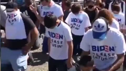 Migrants Kneel At Port Of Entry In Like-New 'Biden Please Let Us In!' T-Shirts