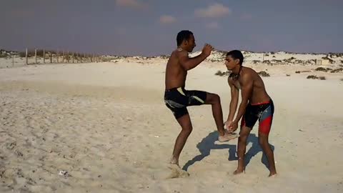 Guy tries to do a backflip at the beach with the help of his friend but fails