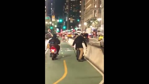 Man standing on skateboard with his luggage uses canes to push himself down street