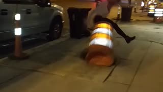 Girl hurdles traffic cone at night falls down on sidewalk