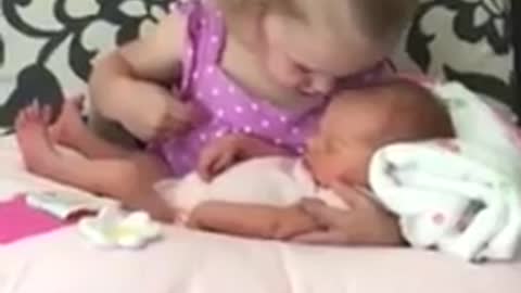 Little girl preciously watches over newborn baby sister