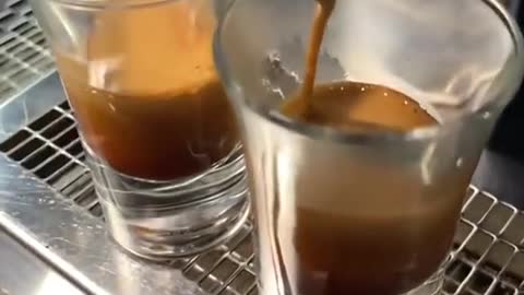 Two cups of espresso flowing slowly