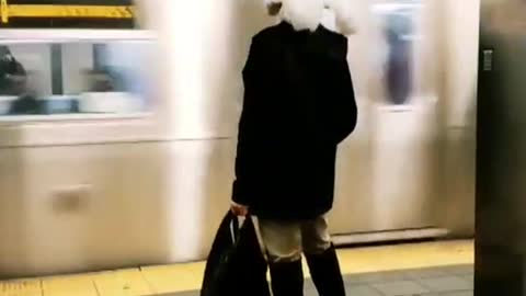 Woman wears a large feather hat at subway station