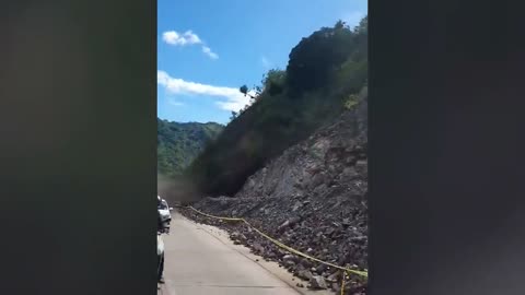 Landslide blocks road while motorists drive after heavy rain in the Philippines