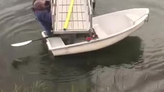 Blue sweater struggles to get white boat under dock
