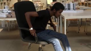 Guy in jeans leans back in office chair and falls