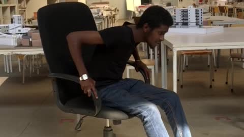 Guy in jeans leans back in office chair and falls