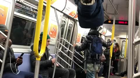 Little boy climbs ceiling handrails and hangs upside down in subway train