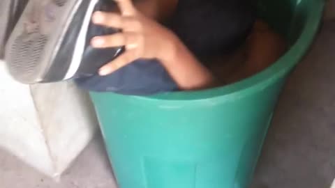 Boy stuck inside green basket tub