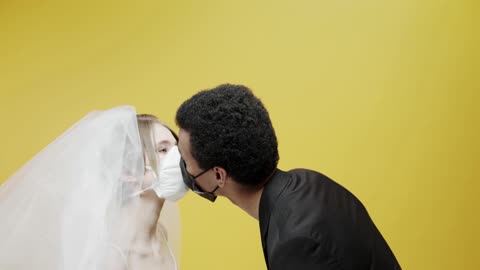 A Newly Wed Couple Kissing While Wearing Face Masks