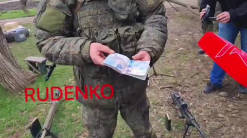 A Russian soldier shows the passport of a killed US mercenary * See Description*