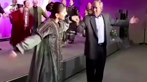 George W. Bush dancing to a Russian folk song with Vladimir Putin in the background