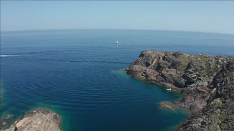 drone flight over motor yacht standing in blue small bag of cap de creus cape to sailboat sailing