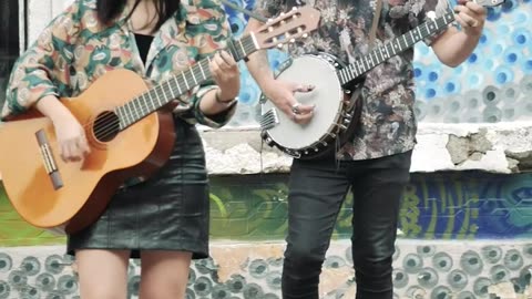 Young man and woman playing music on a colorful street