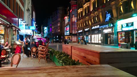 A-WAITRESS-GATHERS-THE-TABLE-AND-CHAIRS-OF-A-RESTAURANT-ARRANGED-IN-THE-SIDEWALK