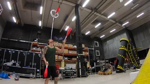 Guy Juggling Clubs While Balancing and Spinning a Ball on Forehead