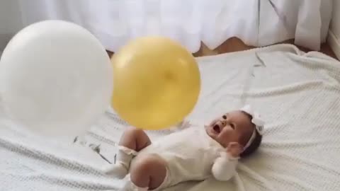 The baby is very happy with a balloon tied to his hand