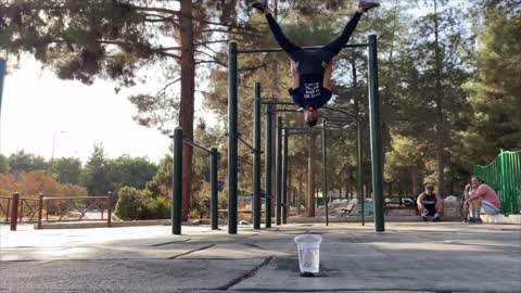 Guy Lands Ball in Cup Using His Mouth Holding Onto Bar Upside Down