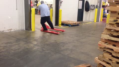 Worker Riding Pallet Jack Slides in Style on Reaching Destination