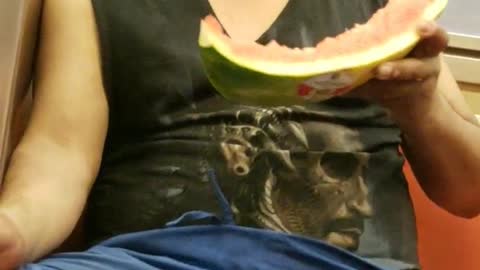 Man on train eating half watermelon