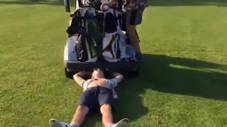 Guy is dragged by golf cart while beer poored into mouth and then hit by following golf cart