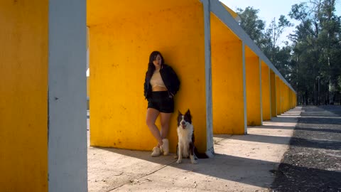A girl and a dog standing in front of a wall