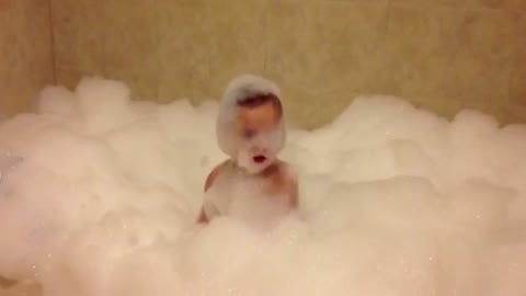 Toddler Enjoys Bubble Bath While Floating On A Cloud Of Foam