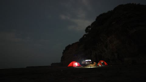 People Camping On A Beautiful Shoreline Beside A Mountain