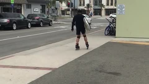Guy on rollerblades with surfboard
