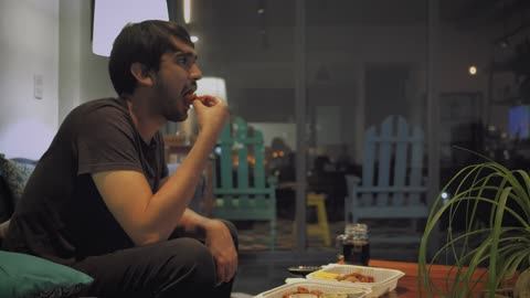 Man eats watching television on a rainy night