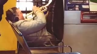 Man doing ab crunches in chair while playing the trumpet